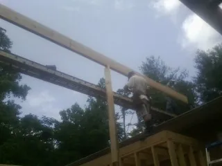 Carpenter setting a ridge beam over a new addition frame — Ice Dam Removal by Roofing Brothers in Cement City