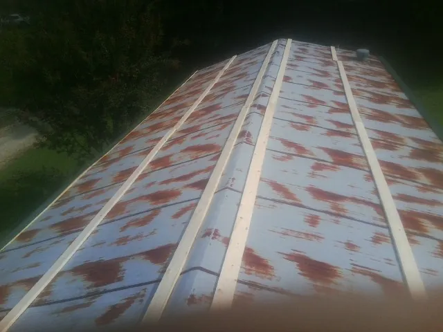Rusted metal roof panels with new wood purlins before replacement — Storm Damage Roof Repair in Cement City by Roofing Brothers