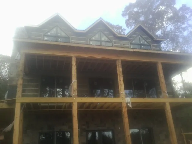 Dormers and porch framing on a large log home under construction — Roof Coating work by our crew in Cement City