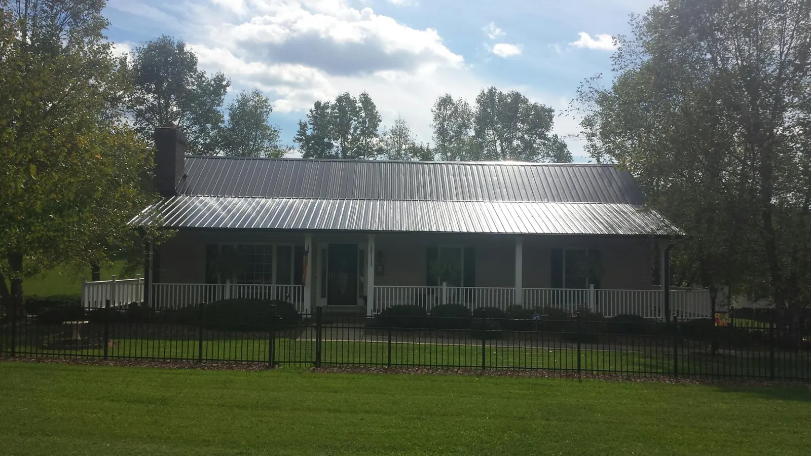 Gray metal roof on a brick ranch with a full width front porch — Gutter Guard Installation work by our crew in Cement City