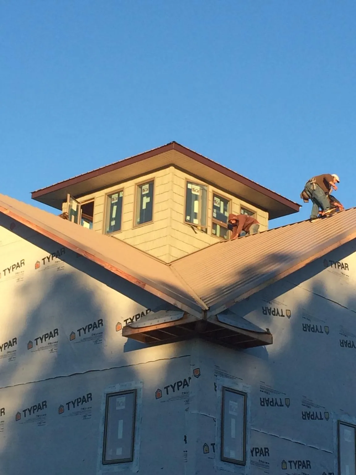 Roofers working around a rooftop cupola on a new metal roof at sunset — Roof Waterproofing in Cement City by Roofing Brothers